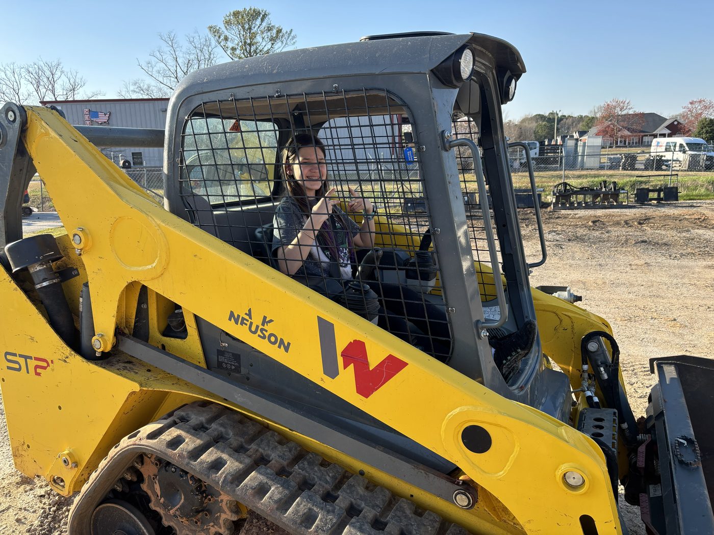 Rene's daughter at the controls of a full-size skid steer at the Bulletproof yard